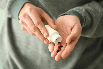 Young man with bottle of pills, closeup