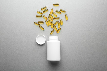 Container with pills on grey background