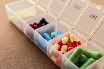 Plastic container with different pills on color background