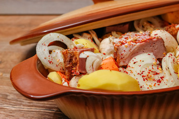Homemade smoked meat and vegetables ready for cooking in ceramic bowl. Sweet and plain potato, carrot, champignon mushrooms garlic and onion.
