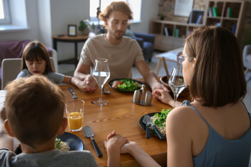 Family praying before meal at home