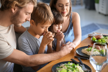 Family praying before meal at home - Powered by Adobe