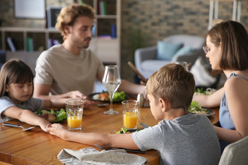 Family praying before meal at home
