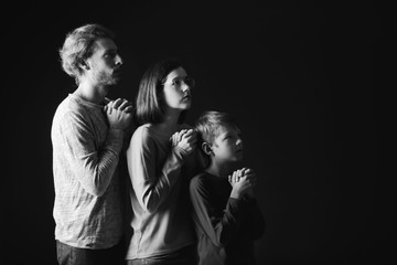 Praying family on dark background