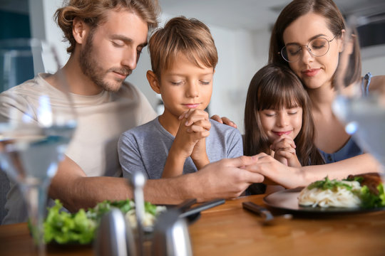 Family Praying Before Meal At Home