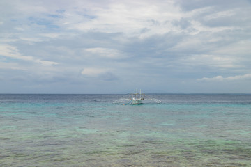 Obraz premium BALICASAG / PHILIPPINES - OCTOBER 30, 2018: Tropical background view from Balicasag island with traditional boats (bancas), blue sky and turquoise sea water, Travel vacation at Philippines.