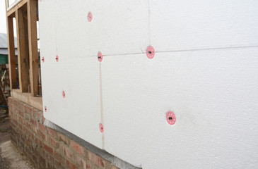 Installing foam insulation board with plastic nails for house energy saving. House foam insulation outdoors.