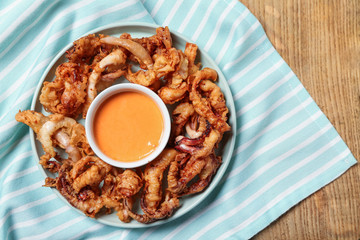 Tasty fried squid with sauce on table