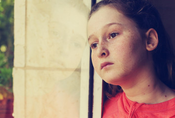 Fototapeta na wymiar Teenager girl sad depressed looking out of a window