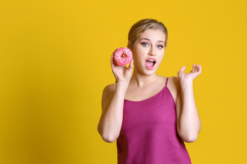 Funny young woman with tasty donut on color background