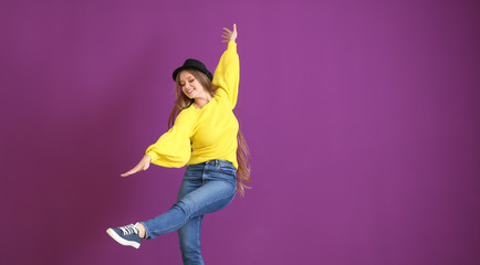 Beautiful young woman dancing on color background