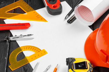 Close up orange hardhat and variety of repair tools with copy space in the middle over wooden  background