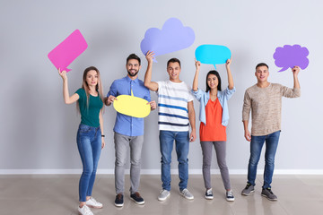 Young people with blank speech bubbles near white wall