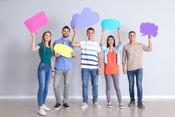 Young people with blank speech bubbles near white wall