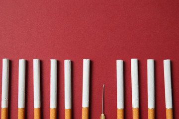 Cigarettes with syringe needle on color background. Concept of addiction
