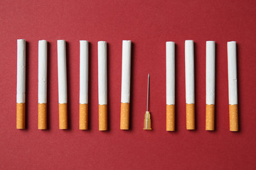 Cigarettes with syringe needle on color background. Concept of addiction
