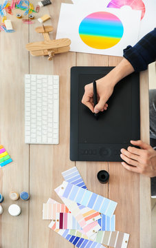 Young designer with graphic tablet working at table