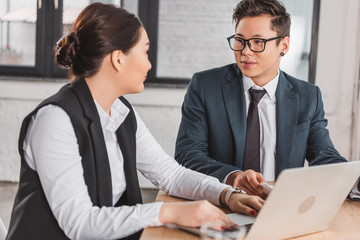 young kazakh business smiling each other while working together in office