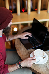 Bearded hipster typing on laptop
