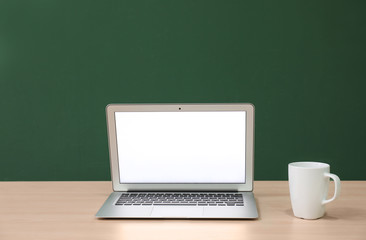 Fototapeta premium Modern laptop on table against color wall