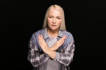 Portrait of beautiful mature woman rejecting something on dark background