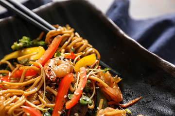 Tasty Chinese noodles with shrimps and vegetables on plate, closeup