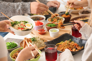 Friends eating tasty Chinese food at table