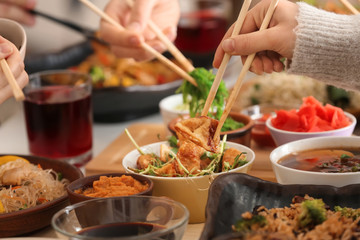 Woman with friends eating tasty Chinese food at table