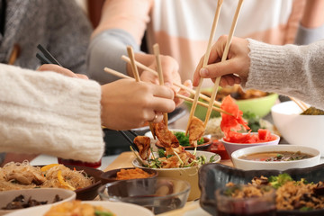 Fototapeta na wymiar Friends eating tasty Chinese food at table