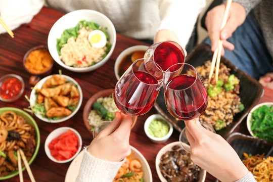 Friends with glasses of wine in Chinese restaurant, closeup