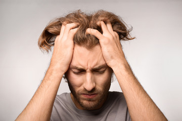 Young man suffering from headache on light background