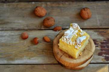 Piece of apple pie with orange sprinkled with powdered sugar on a wooden background