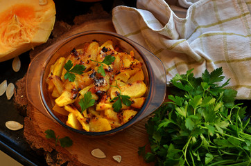 Pumpkin casserole in aheatproof dish on a wooden disc