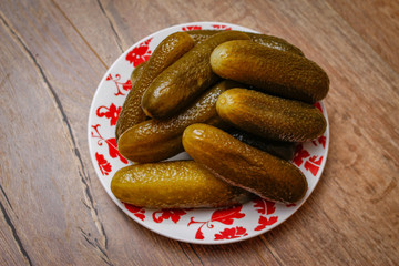 Pickled cucumber in a porcelain plate on vintage wooden table