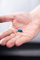 Fototapeta Niebieska tabletka. Mężczyzna trzyma w dłoni tabletkę obraz