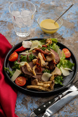 Salad with warm beef with oyster mushrooms, tomatoes and greens.