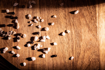 Sól kuchenna. Kompozycja kryształków soli i ziaren pieprzu  na drewnianym blacie.