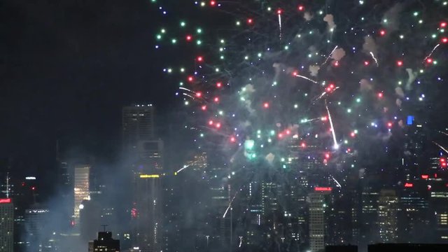 Dask night sky over Sydney city CBD illuminated by bright midnight new year fireworks during celebration.
