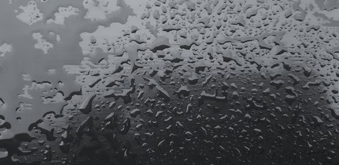 Close up raining water drop on the wooden or stainless steel surface after rainy day in black and white style for background  - Art, Abstract and Wallpaper concept 