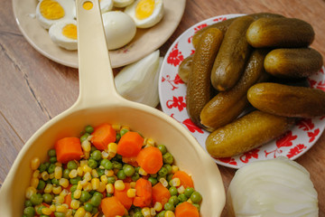 Cooked vegetables, boiled eggs and pickles. Ready components for russian salad, on vintage wooden table.