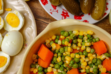 Cooked vegetables, boiled eggs and pickles. Ready components for russian salad, on vintage wooden table.