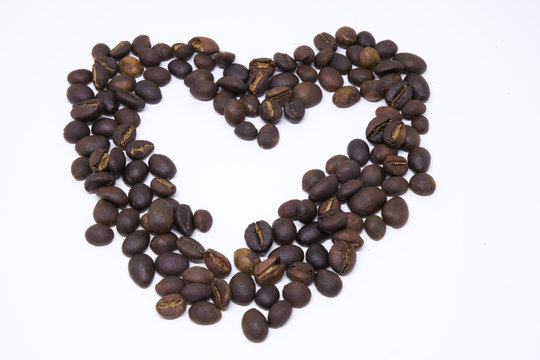 Heart shape draw by coffee beans. Royalty high-quality free stock macro photo image shape heart love design text by roasted black coffee bean on white background. Close-up or macro photo coffee beans