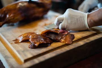 The chef is cutting the duck skin from the Beijing duck with a very sharp knife at a famous Chinese restaurant.