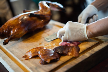 The chef is cutting the duck skin from the Beijing duck with a very sharp knife at a famous Chinese restaurant.