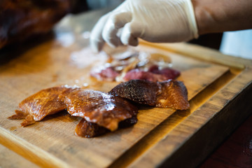 The chef is cutting the duck skin from the Beijing duck with a very sharp knife at a famous Chinese restaurant.