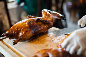 The chef is cutting the duck skin from the Beijing duck with a very sharp knife at a famous Chinese restaurant.