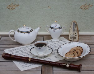 English teacup with saucer, teapot, sugar bowl and a cake bowl, fine bone china porcelain, metronome for music and a block flute on a sheet of music