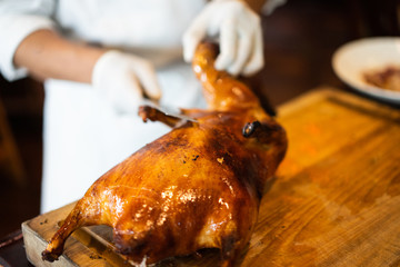 The chef is cutting the duck skin from the Beijing duck with a very sharp knife at a famous Chinese restaurant.