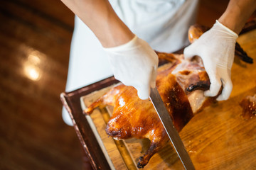 The chef is cutting the duck skin from the Beijing duck with a very sharp knife at a famous Chinese restaurant.