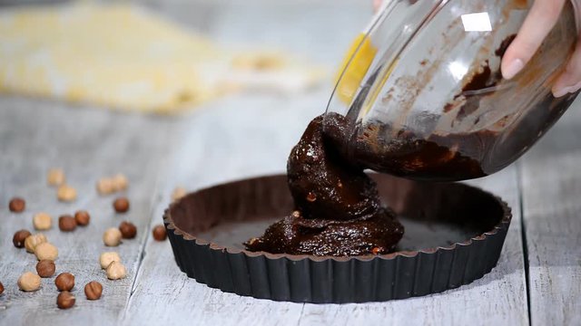 Pouring chocolate batter over top. Making Chocolate Tart.